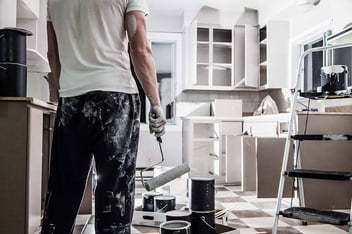 A man increases his property value by painting his kitchen.