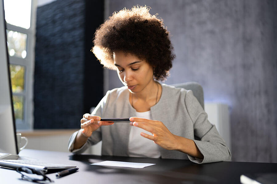 After learning how to endorse a check for mobile deposit, a woman uses her smart phone to deposit a check remotely.